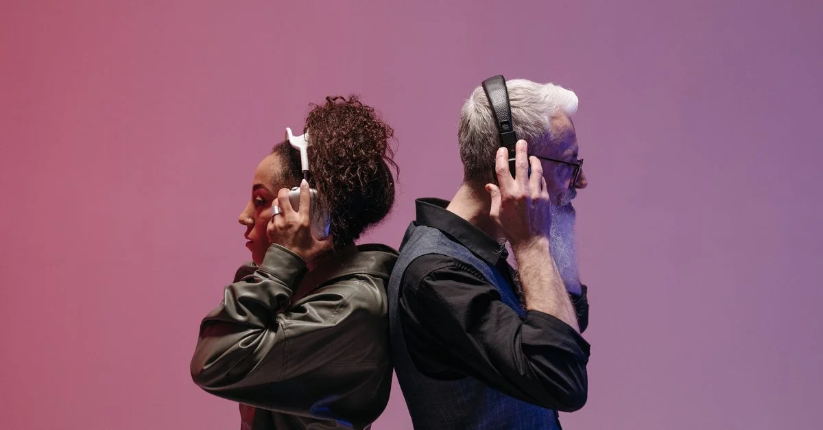 Un homme et une femme se tenant dos à dos, profitant de casques sans fil sur un fond rose.